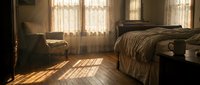 Cozy bedroom interior with warm sunlight streaming through windows, creating dramatic shadows on wooden floor. Rustic furniture and neutral bedding.