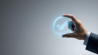 Businessman hand holding glowing checkmark symbol on sphere, representing approval, quality assurance, and successful business validation for corporate concepts.