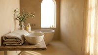 Spa bathroom interior with natural light from arched window, featuring folded towels, ceramic bowl, glass bottles, and fresh greenery on wooden shelf for wellness and relaxation design.
