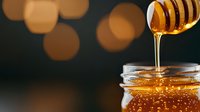 Golden honey dripping from wooden dipper into glass jar with warm bokeh lights creating cozy atmosphere for natural sweetness and organic food concepts.