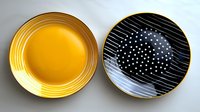 Stylish ceramic plates with modern design featuring yellow gold and black colors with geometric patterns, stripes, and polka dots on white background.