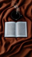 Open book with steaming black coffee cup on brown silk fabric background, creating cozy reading atmosphere for lifestyle and relaxation concepts.