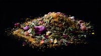 Aromatic herbal tea blend with dried rose petals, chamomile flowers and loose herbs scattered on dark background, macro food photography with natural lighting.
