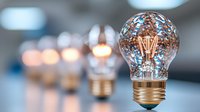 Glowing vintage light bulb with filament in warm golden color against blurred background of multiple bulbs creating bokeh effect. Creative innovation concept.