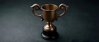 Bronze trophy cup with ornate handles on dark background symbolizing victory, achievement, competition success, and winning excellence in sports or business.