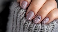 Trendy mauve nail art with white polka dots and love text on ring finger, short square manicure against cozy knitted sweater background.