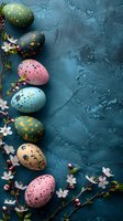 Decorated Easter eggs in pastel colors with gold speckles arranged with spring cherry blossoms on dark teal textured background. Seasonal holiday composition.
