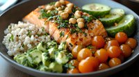 Healthy buddha bowl with grilled salmon, brown rice, chickpeas, cherry tomatoes, cucumber, avocado and fresh herbs arranged in sections, nutritious meal.