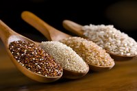 Wooden spoons filled with various types of quinoa and ancient grains showing texture and variety against dark background, macro food photography for cooking blogs.
