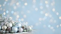 Frosted ornaments and evergreen branches arranged on wooden surface with soft bokeh lights, suitable for holiday greeting cards, seasonal marketing, and festive website backgrounds.