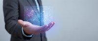 Businessman in dark suit holding glowing digital hologram with network icons and data visualization, representing technology innovation and business solutions.