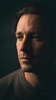 Dramatic portrait of middle-aged Caucasian man with intense gaze and stubble in moody lighting. Professional headshot for corporate and editorial use.