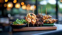 Grilled shrimp and beef skewers served on wooden board with fresh herbs and dipping sauce, bokeh lights in background create warm restaurant ambiance.