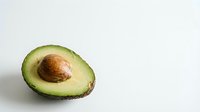 Fresh ripe avocado half with pit on clean white background isolated for healthy cooking and nutrition design projects.