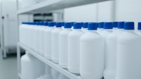 Row of white plastic bottles with blue caps on laboratory shelf, selective focus. Clean medical or pharmaceutical containers in sterile environment for medicine production.