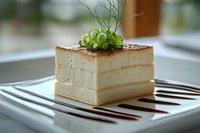 Elegant layered vanilla cake slice with microgreens garnish on white plate, gourmet dessert presentation for fine dining restaurant menu.