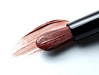 Makeup brush with brown powder stroke on white background, professional cosmetic application tool showing texture and pigment application.