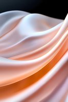 Smooth flowing curves of peach and white silk fabric create elegant waves and soft folds against dark background, presenting luxurious textile movement and light play.