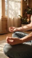 Woman practicing yoga meditation in lotus pose at home with warm sunlight streaming through window creating peaceful wellness atmosphere.