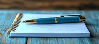 Elegant blue and gold pen resting on open spiral notebook with blank white pages against rustic turquoise wooden surface, shallow depth of field creates dreamy atmosphere.