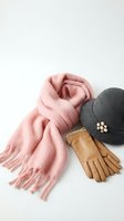 Pink knitted scarf with fringe, black hat with pearl brooch and brown leather gloves isolated on white background for fashion and winter accessories design.