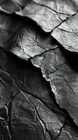 Dramatic black and white macro photography of crumpled paper texture with deep shadows and intricate network of creases creating abstract geometric patterns.
