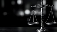 Bronze scales of justice on dark surface with blurred lights background symbolizing law, legal system, court proceedings and judicial balance.