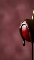 Chocolate covered strawberry on stick with melting dark chocolate dripping against burgundy background for romantic dessert and Valentine's Day treats.