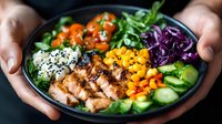 Fresh poke bowl with grilled chicken, mango, red cabbage, cucumber, rice and sesame seeds. Healthy balanced meal served in dark ceramic bowl.