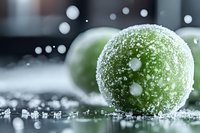 Fresh green limes covered in crystalline frost and water droplets on dark reflective surface with bokeh lights creating magical winter atmosphere.