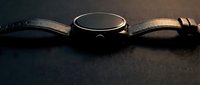 Elegant black smartwatch with leather strap on dark surface, modern wearable technology device for fitness tracking and connectivity.