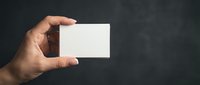Hand holding blank white business card mockup against dark textured background for branding and corporate identity design projects.