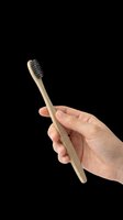 Eco-friendly bamboo toothbrush with black bristles held in hand, isolated on transparent background. Ready for dental care, wellness, and sustainable lifestyle designs, clipart, and print-on-demand products.