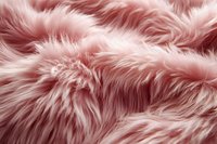 Soft pink faux fur texture background with fluffy fibers and gentle waves creating luxurious plush surface for fashion and interior design projects.