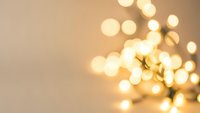 Warm golden bokeh lights creating soft blurred circles on neutral beige background for holiday decorations and festive seasonal designs.