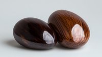 Polished wooden eggs with natural grain pattern on neutral background, decorative home accessories and craft objects for interior styling and design.
