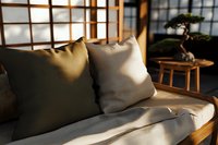 Cozy wooden sofa with beige cushions in sunlit Japanese style room with shoji screens and bonsai tree creating peaceful zen atmosphere for interior design.