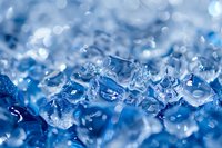 Macro shot of melting ice crystals with blue tones and bokeh effect creating abstract winter background pattern. Natural frozen water texture with soft focus details.