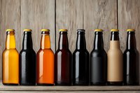 Row of assorted craft beer bottles showing different styles from light lager to dark stout on rustic wooden background, cold drinks with condensation.