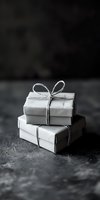 Minimalist stacked gift boxes wrapped in gray paper with simple twine bows on dark textured background, moody atmospheric holiday composition.