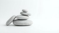 Stacked smooth gray stones balanced on white background, symbolizing zen, meditation, wellness, and spa relaxation therapy.