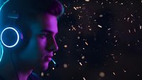 Young man with headphones in neon purple and blue lighting with golden particles, gaming setup, music production, DJ lifestyle, modern technology concept.
