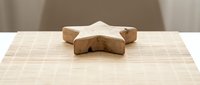Wooden star-shaped toy block on bamboo mat surface for educational play and child development activities in minimalist setting.