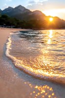 Golden sunset over mountain beach with waves gently rolling onto shore, creating sparkling reflections on wet sand as sun rays pierce through clouds.