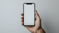 Hand holding modern smartphone with blank white screen against neutral gray background, mockup for app and website presentation.