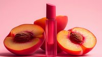 Pink lip gloss tube with fresh peach slices on soft pink background for beauty and cosmetics advertising campaigns.