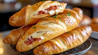 Fresh baked stuffed bread rolls with melted cheese and meat filling on woven basket, golden brown crust, close up view of artisanal bakery product.