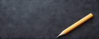 Single wooden pencil with sharp graphite tip positioned diagonally on dark textured slate surface for creative writing and drawing projects.