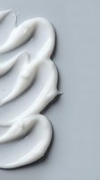 White creamy cosmetic texture swirl on gray background for skincare beauty product advertising and packaging design applications.