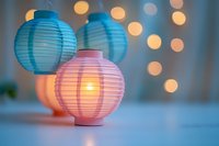 Glowing pink and blue paper lanterns with soft bokeh lights in background create magical festive atmosphere for party or celebration decor.
